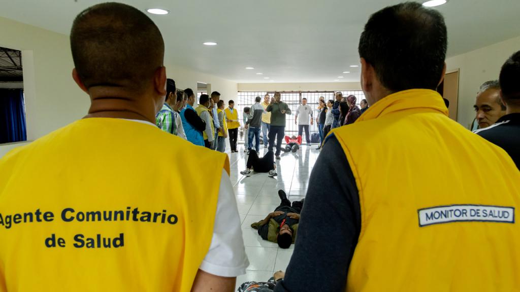 Two men wearing yellow vests on which are written the words Community Health Agent.