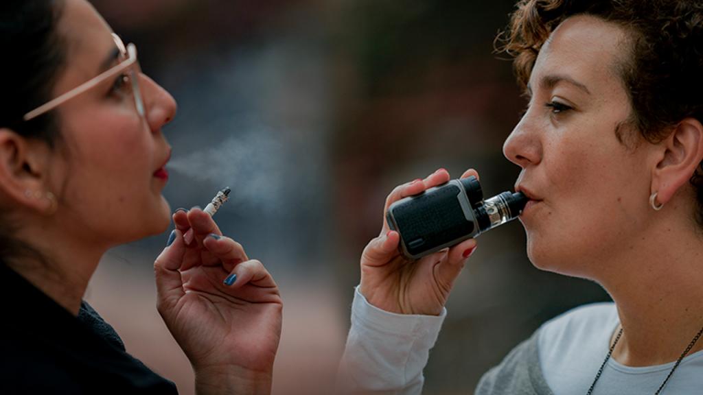 Woman smoking in front of a woman vaping