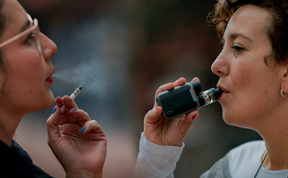 Woman smoking in front of a woman vaping