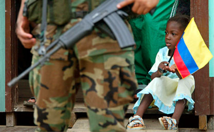 Afrocolombian little girl holding the national flag alongside a soldier