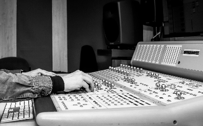 Hands control an audio recording console in the Los Andes studio.