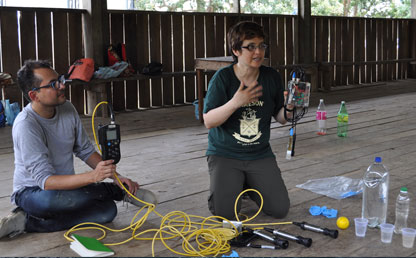 A kneeling woman holds a sensor and explains its use to an Amazon community.