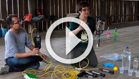 A kneeling woman holds a sensor and explains its use to an Amazon community.