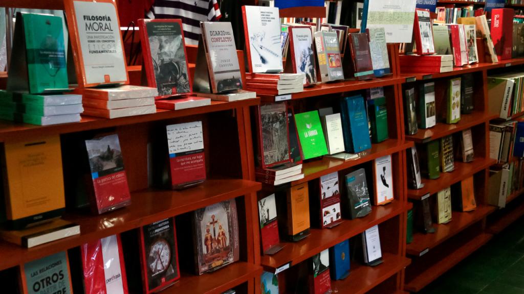 A shelf full of books that are published by the Uniandes publishing house.